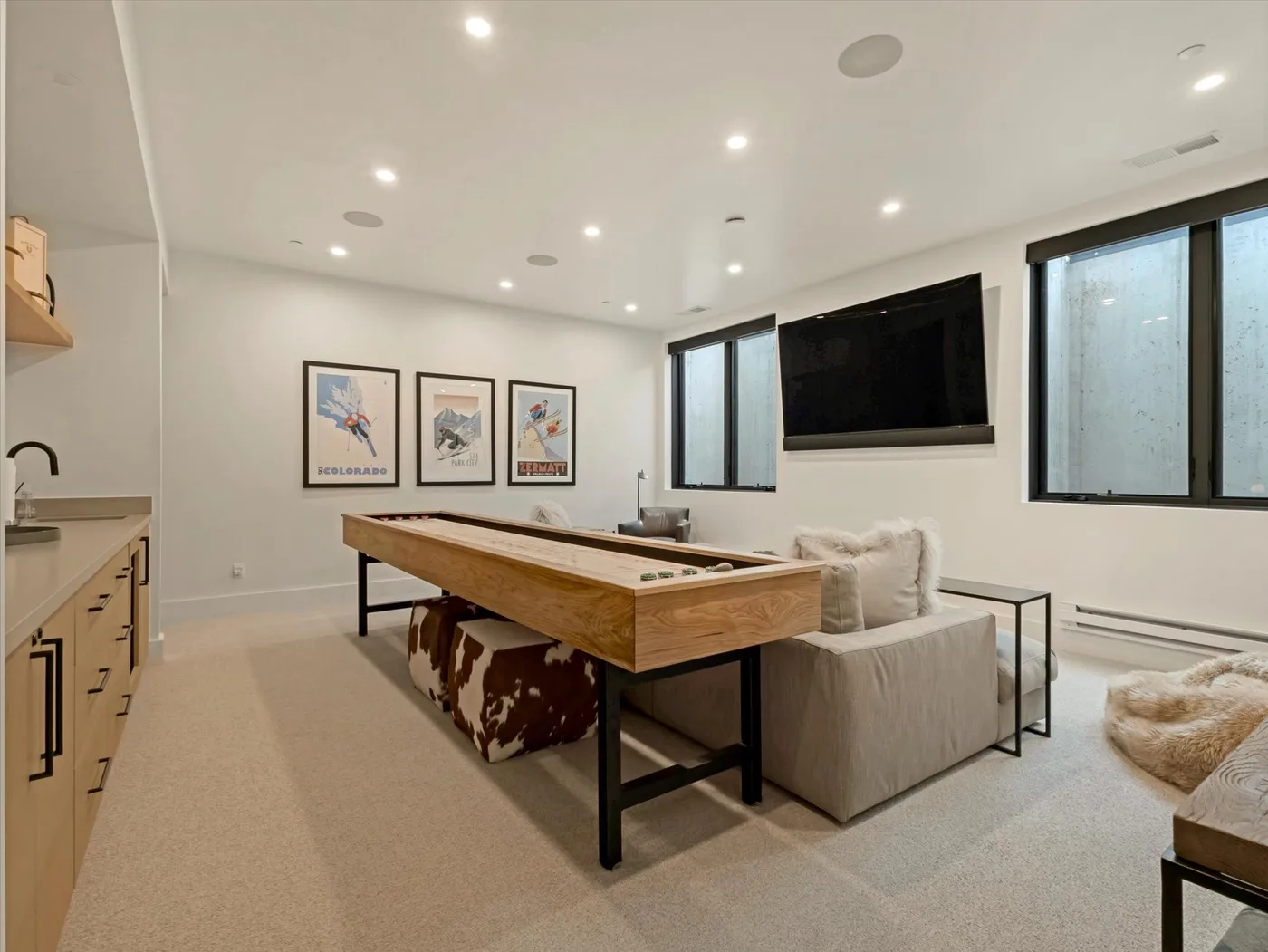 A bright recreation room features a pool table, seating, and a wall-mounted television.