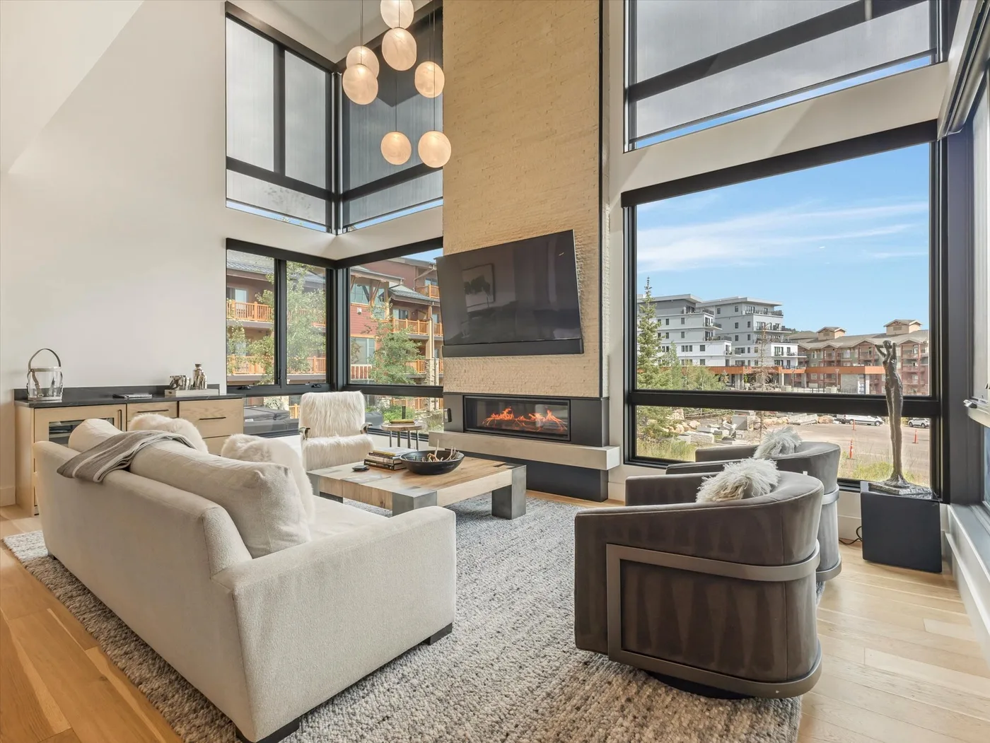 A bright living room with tall windows, seating, and a fireplace.