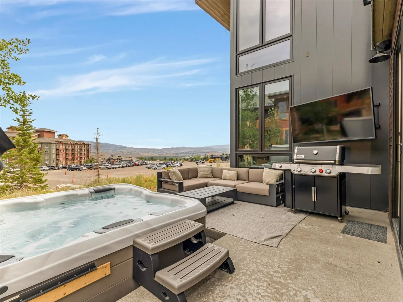 An outdoor patio features a hot tub, seating, and a grill.