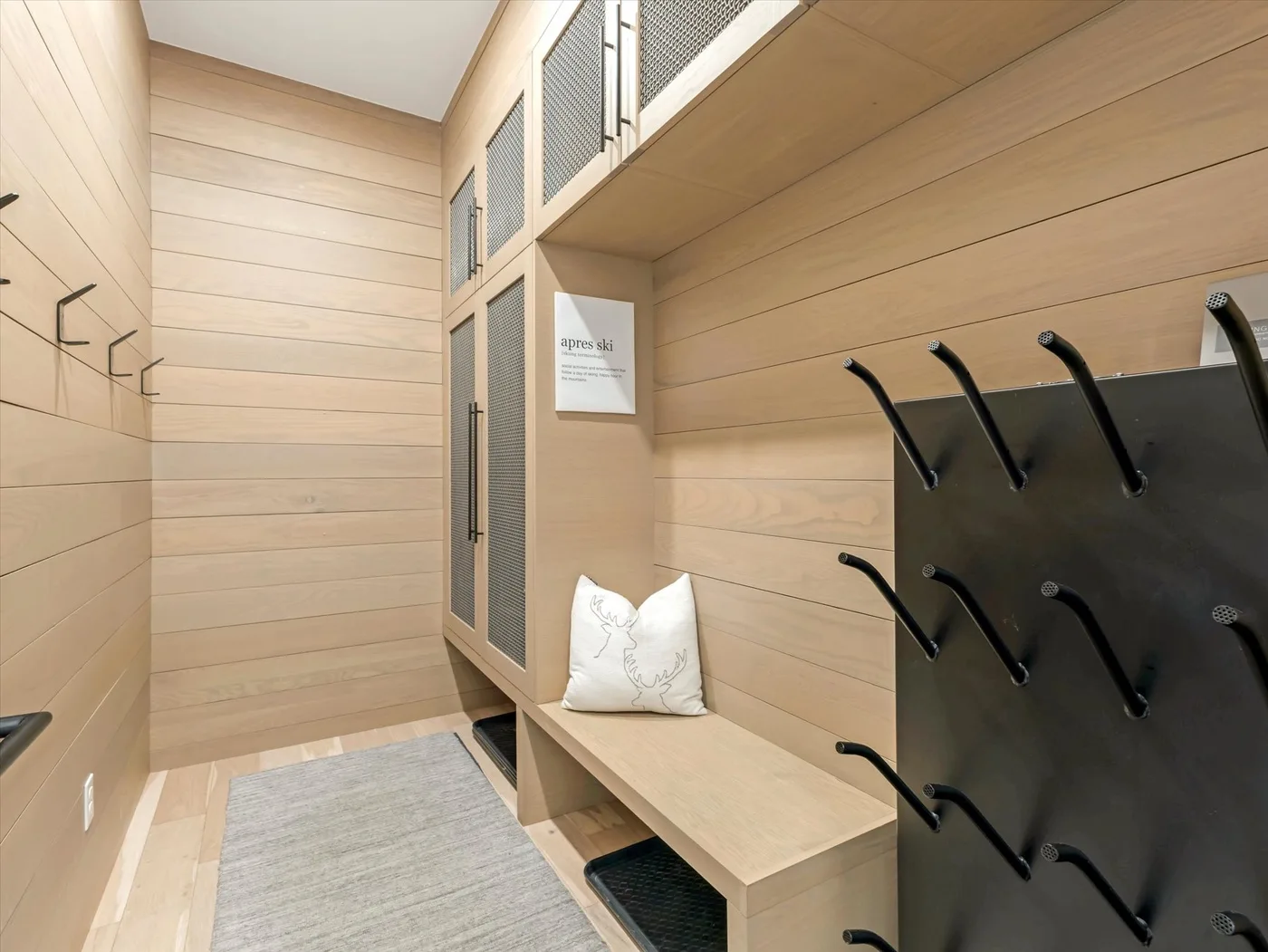 A wood-paneled entry area has a bench and wall-mounted hooks.