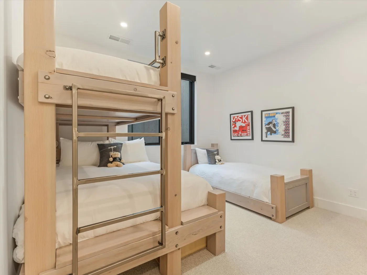 A bedroom with wooden bunk beds and a separate bed beneath framed wall art.