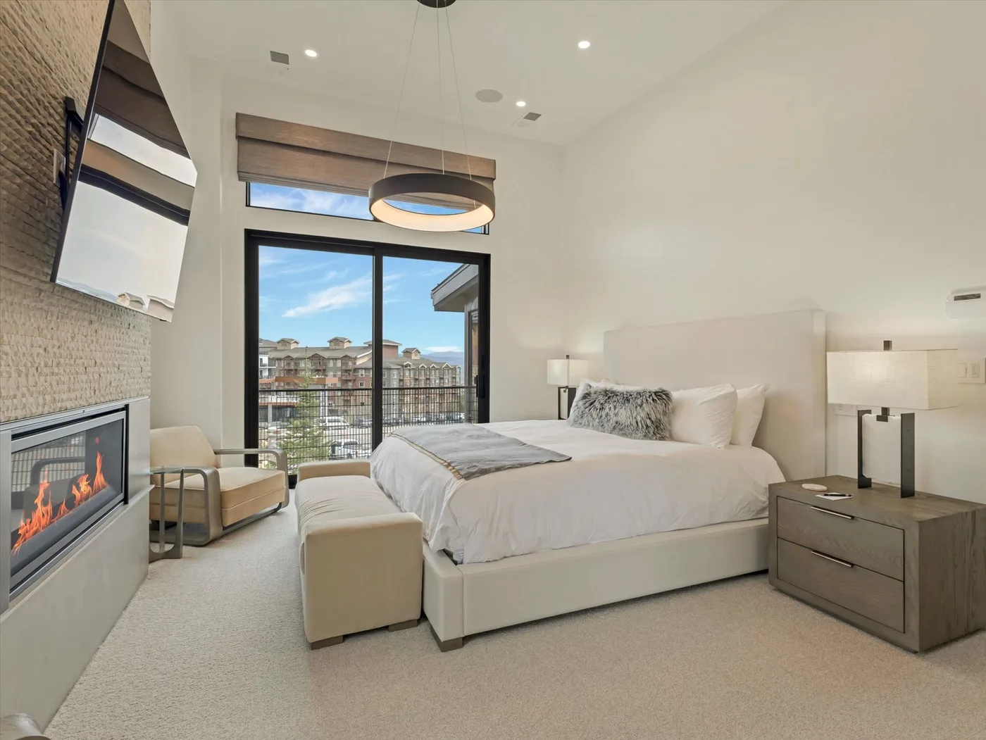 A bright bedroom with a bed, seating, and a large window.