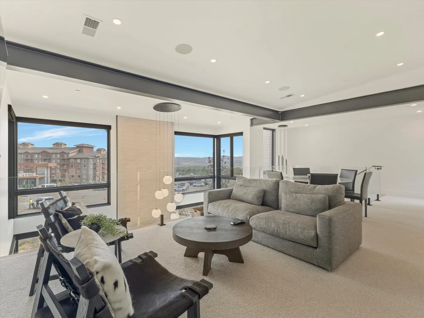 A bright living room has seating around a coffee table beside large windows.