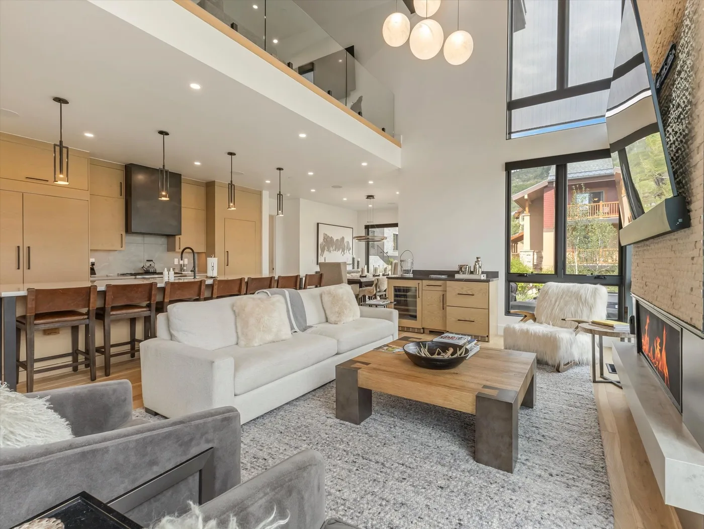 A bright double-height living room with a white sofa and a wooden coffee table.
