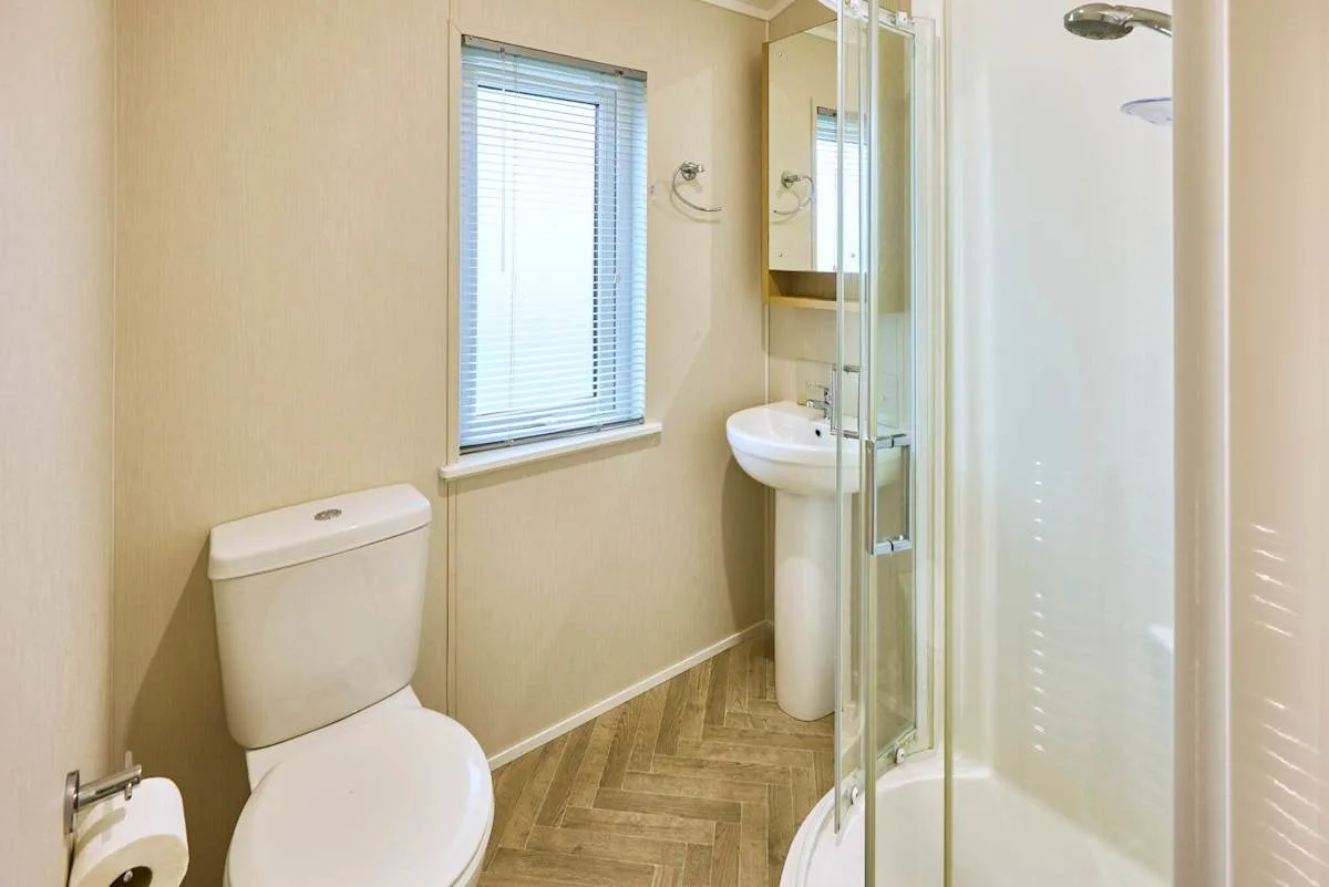 Un baño con inodoro, lavabo de pedestal y ducha de vidrio.