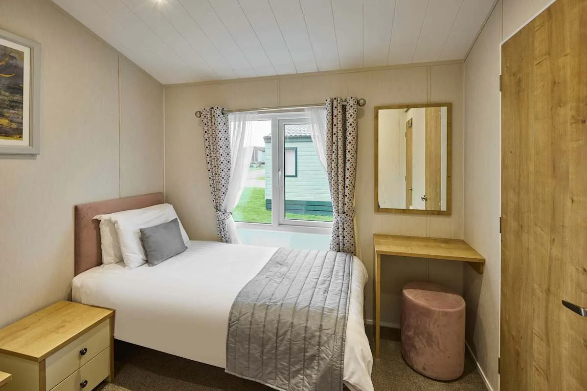 Un dormitorio con una cama, una ventana y un pequeño tocador.