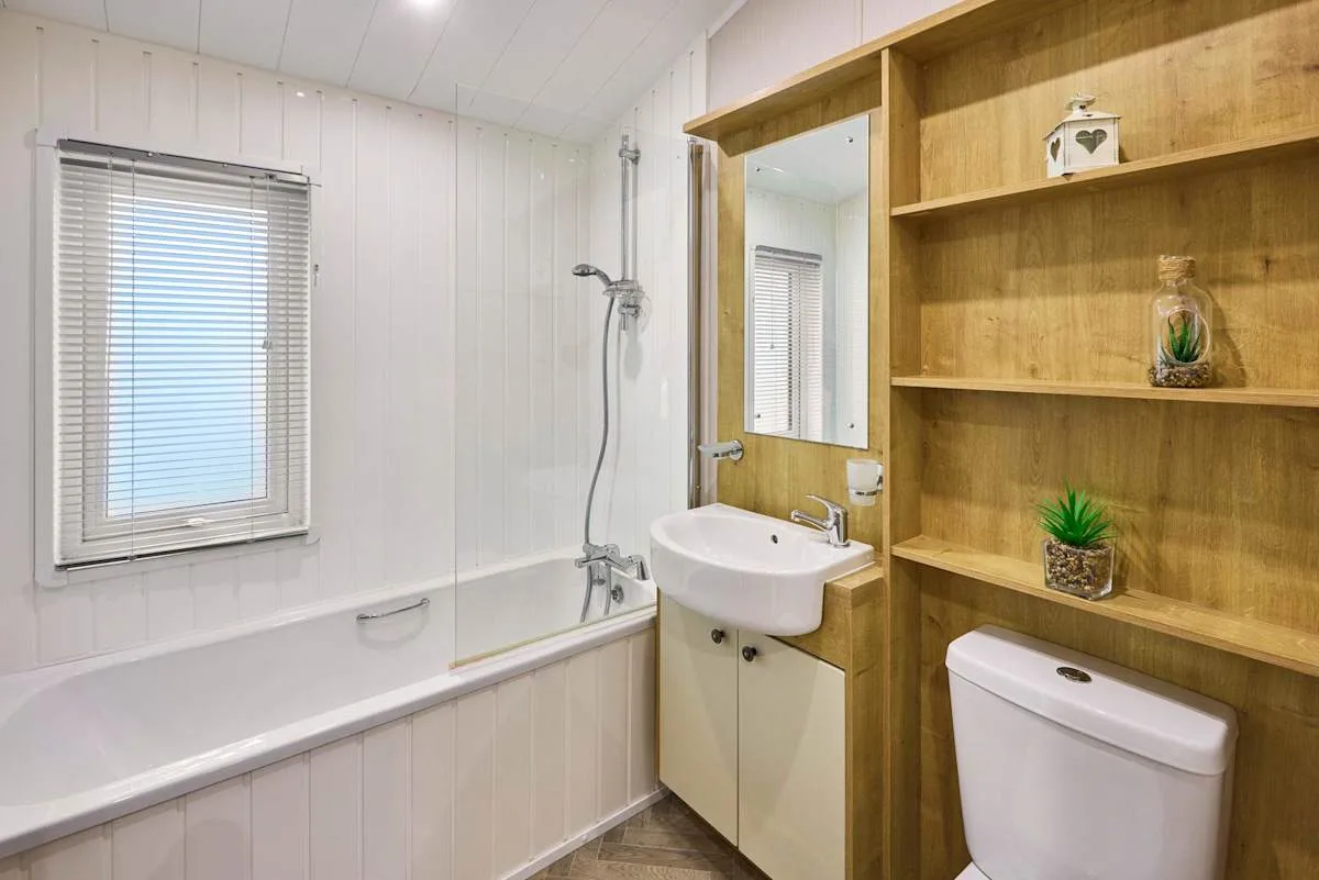 Un baño con bañera, lavabo y estanterías de madera.