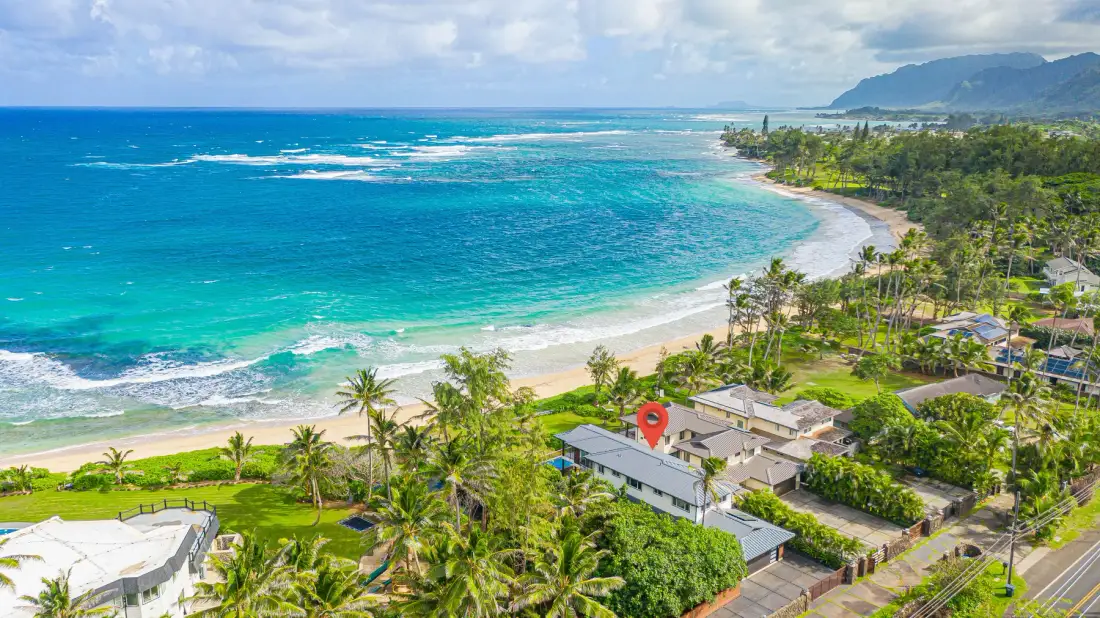 Una costa tropical con aguas turquesas, una playa de arena y palmeras.