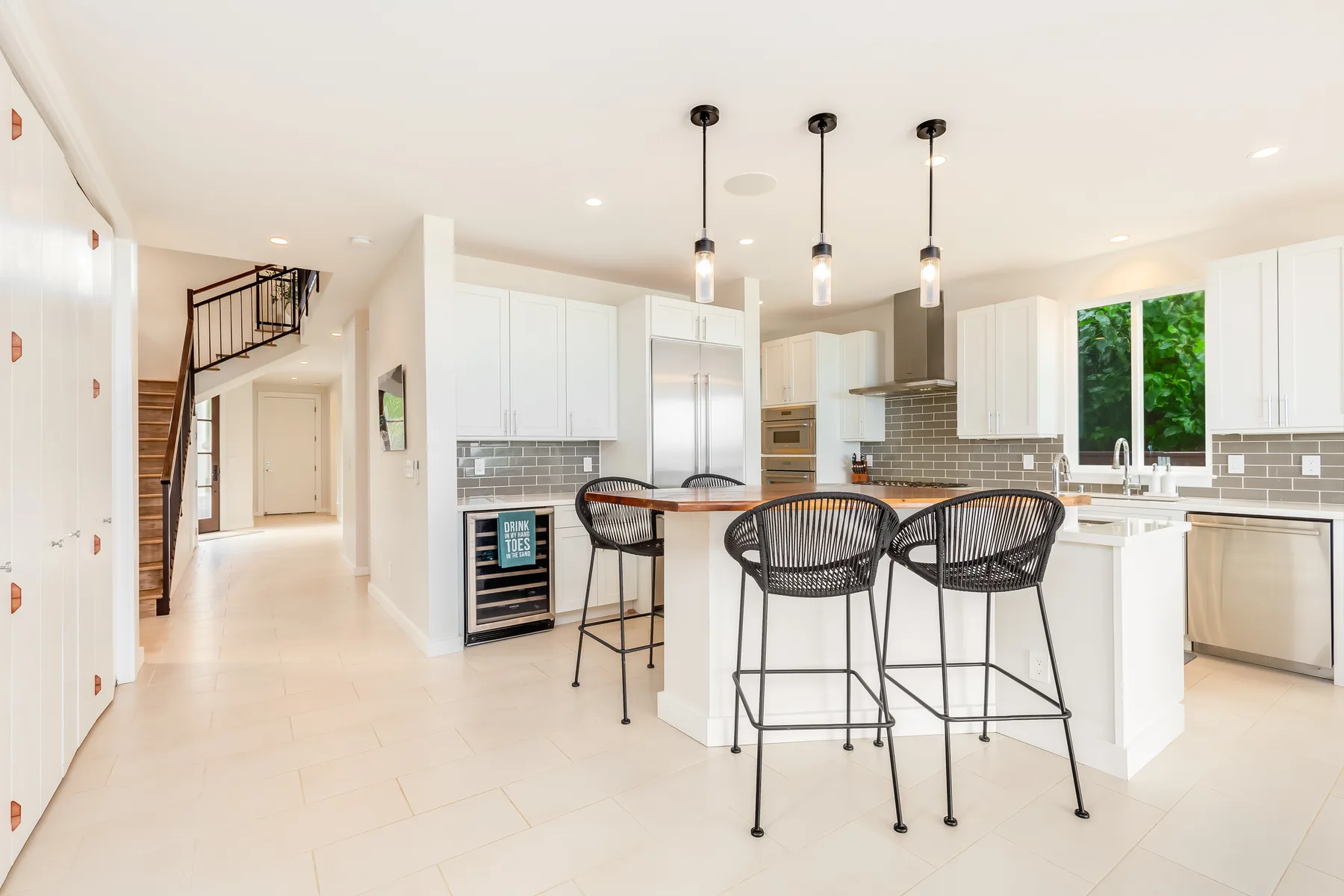 Una cocina luminosa con una isla central y asientos altos oscuros.