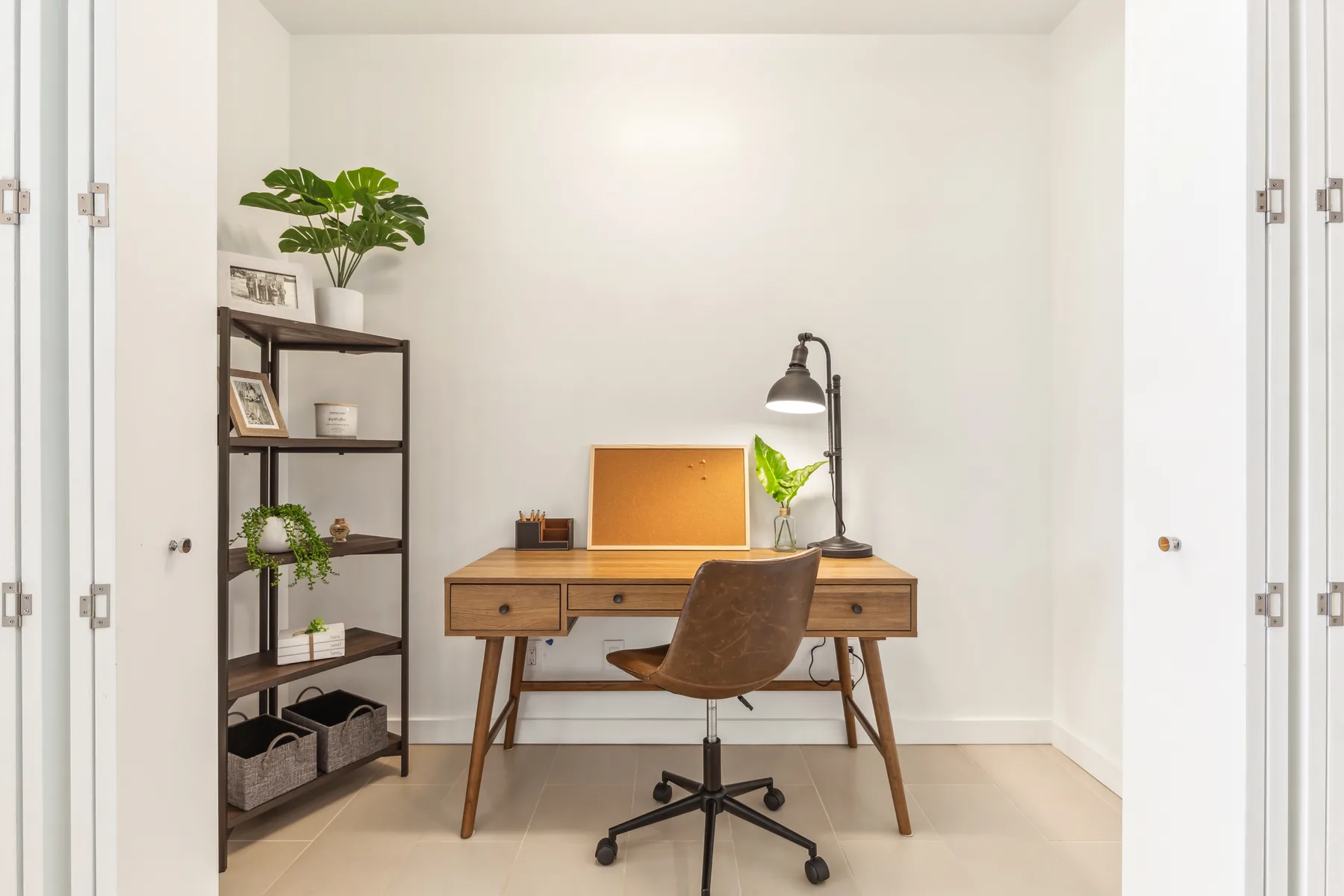 Un espacio de trabajo luminoso con escritorio de madera, silla con ruedas y estantería.