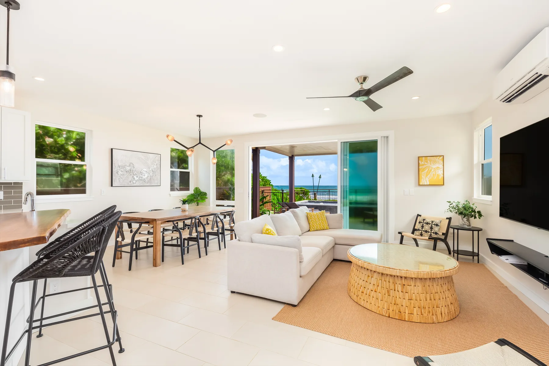 An open living and dining area with seating, a table, and sliding doors overlooking the water.