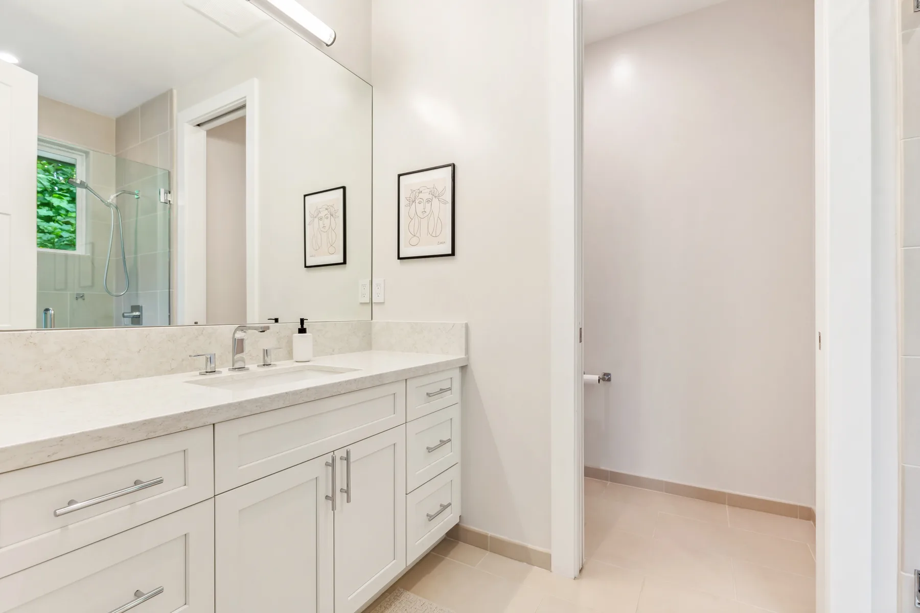 Un lavabo de baño luminoso está junto a una pared con espejo y una puerta abierta.