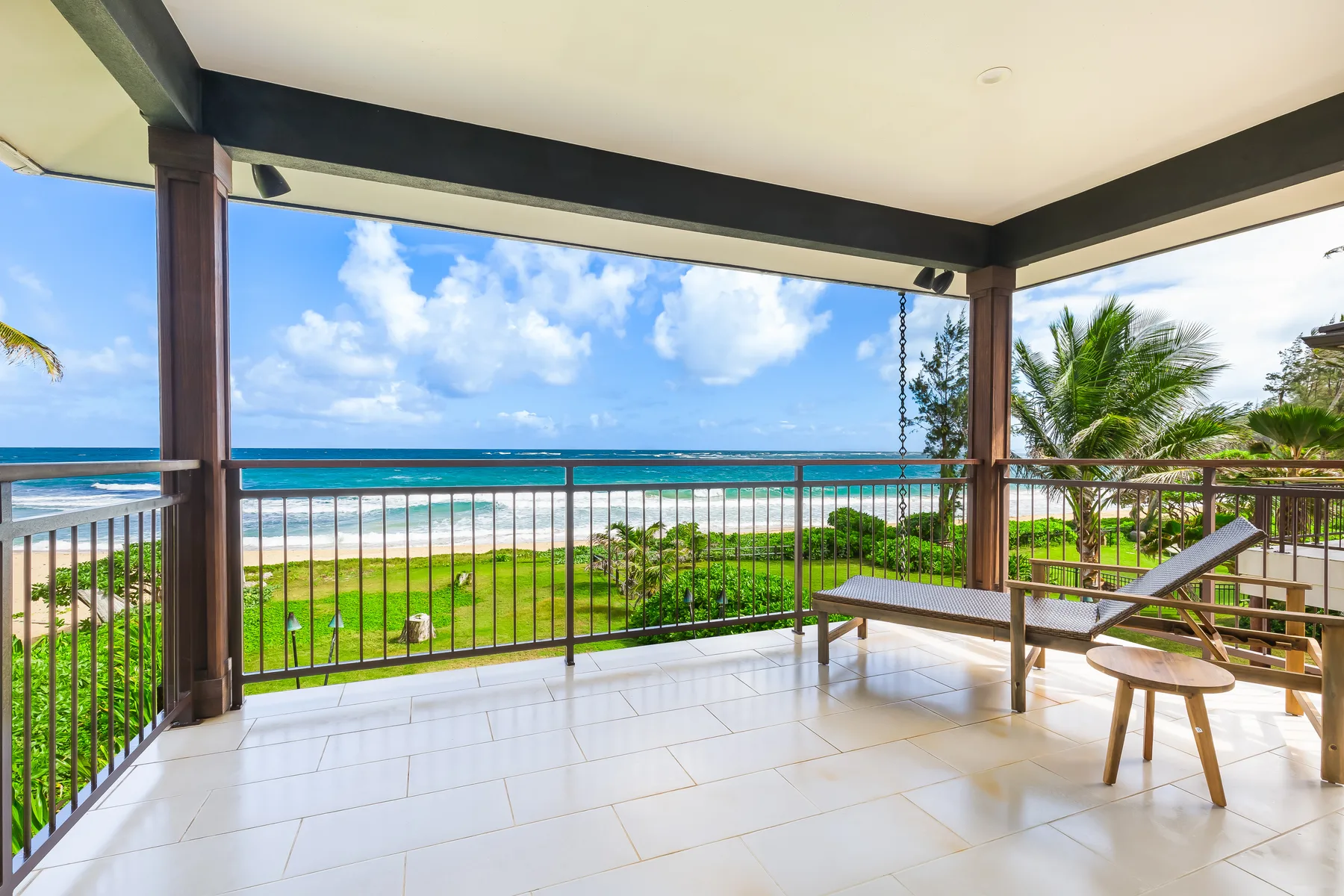 A covered beachfront terrace with tiled flooring and a view of the ocean.