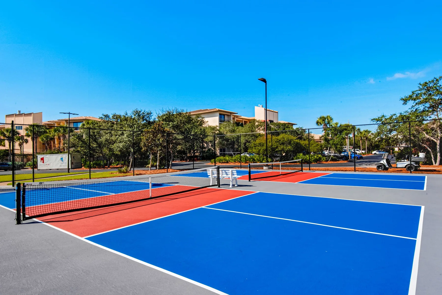 Outdoor sports courts with blue and red playing surfaces and nets.