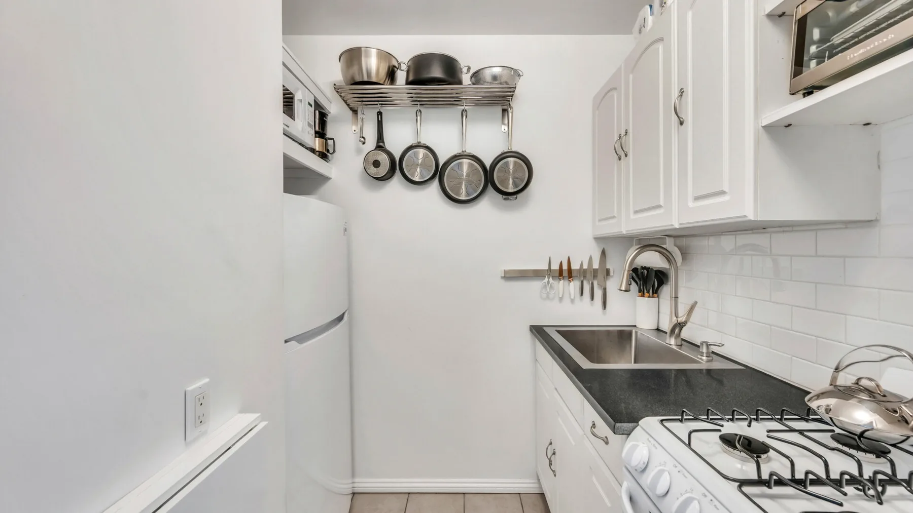 A compact kitchen with white cabinets, a sink, and a gas cooktop.