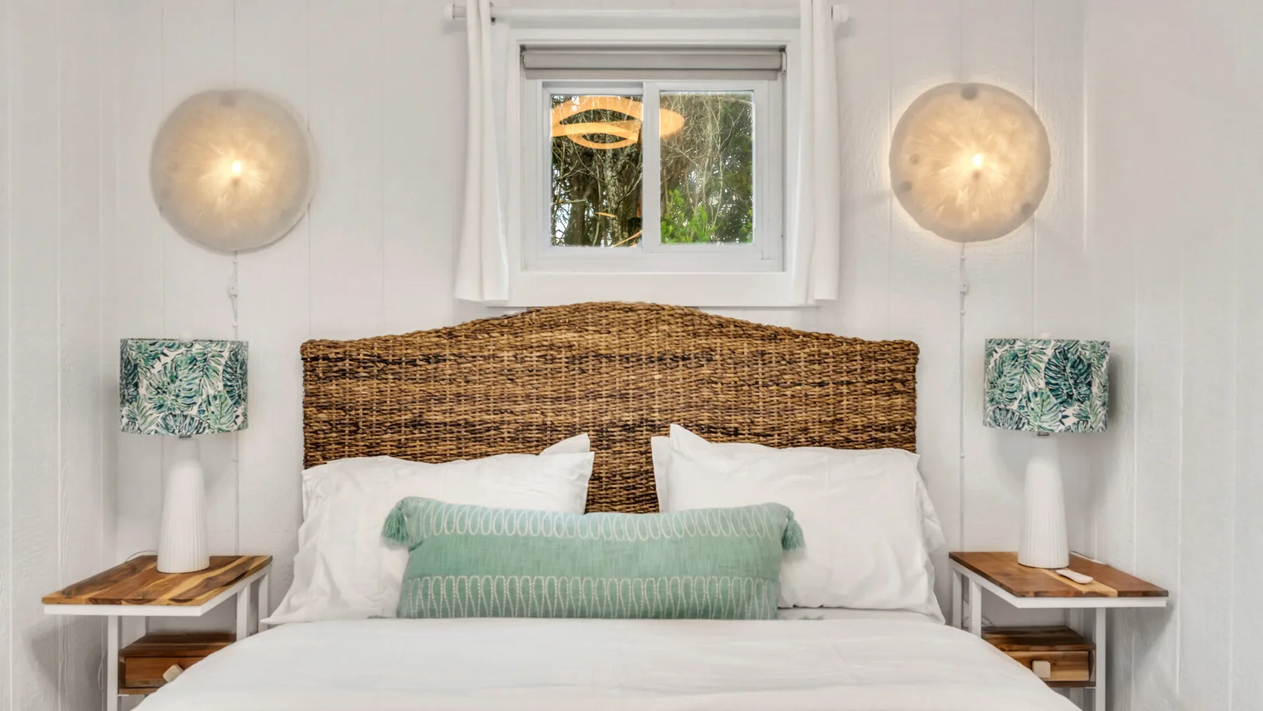 A bedroom with a bed, woven headboard, and matching bedside tables.