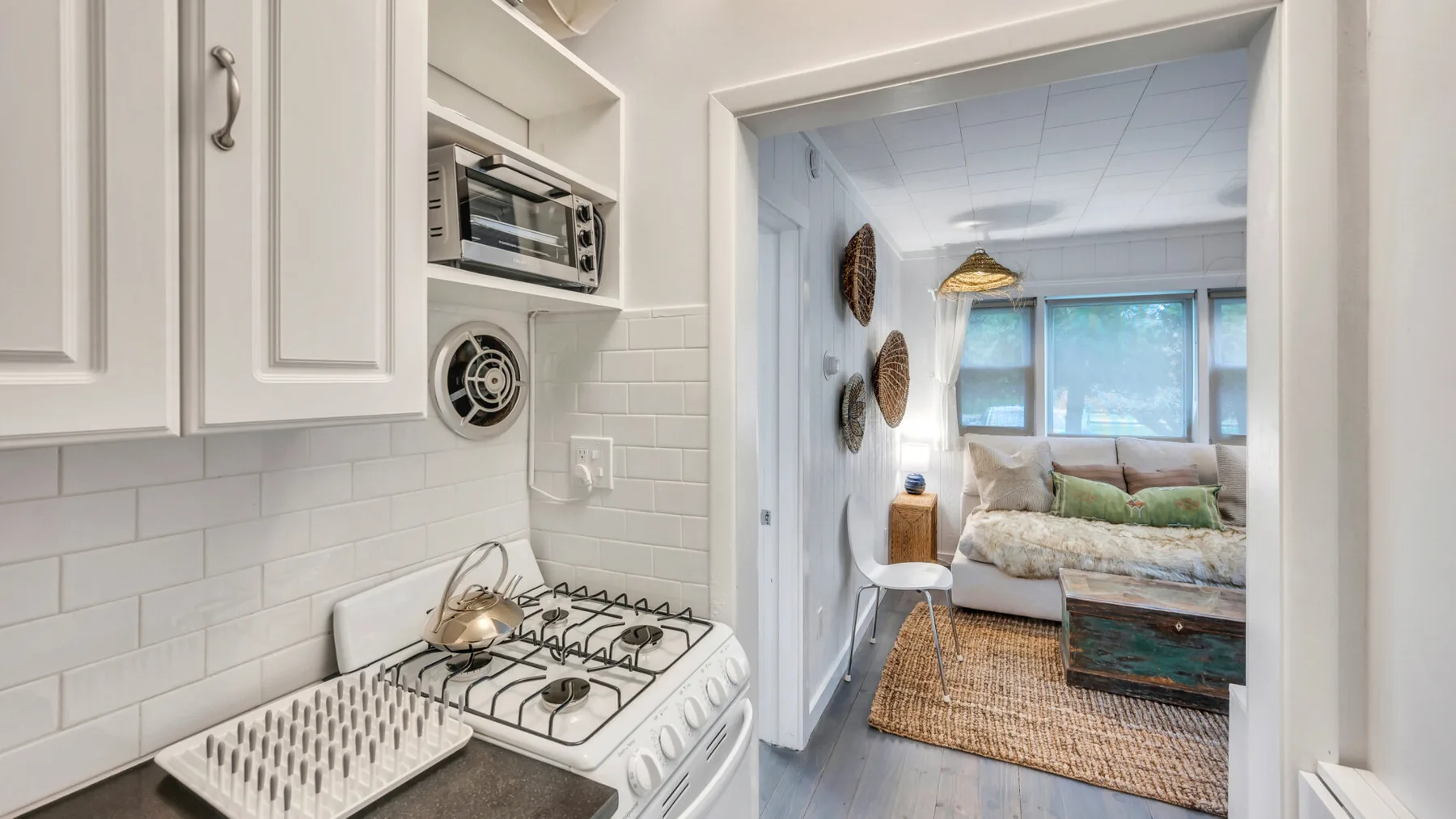 A compact kitchen opens into a living area with a sofa and rug.