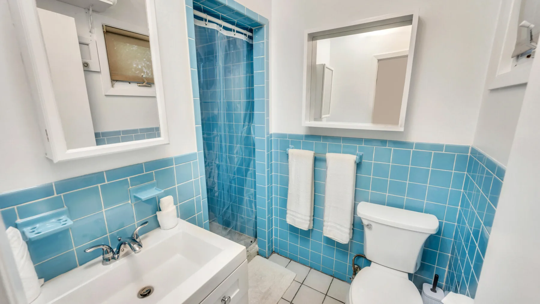 A bathroom with a sink, toilet, and blue tiled walls.