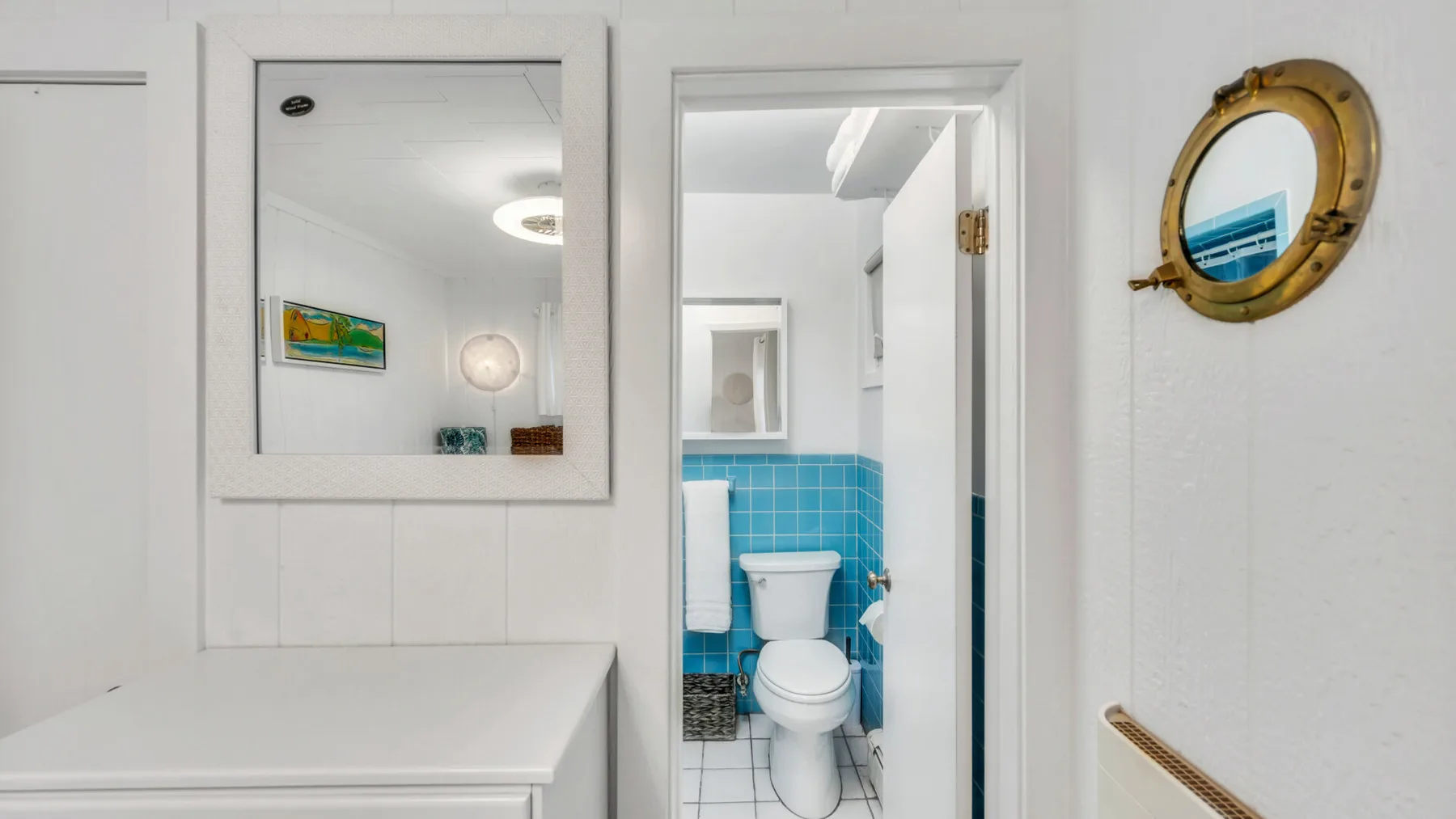 A bright bathroom with blue tiled walls and a white toilet.