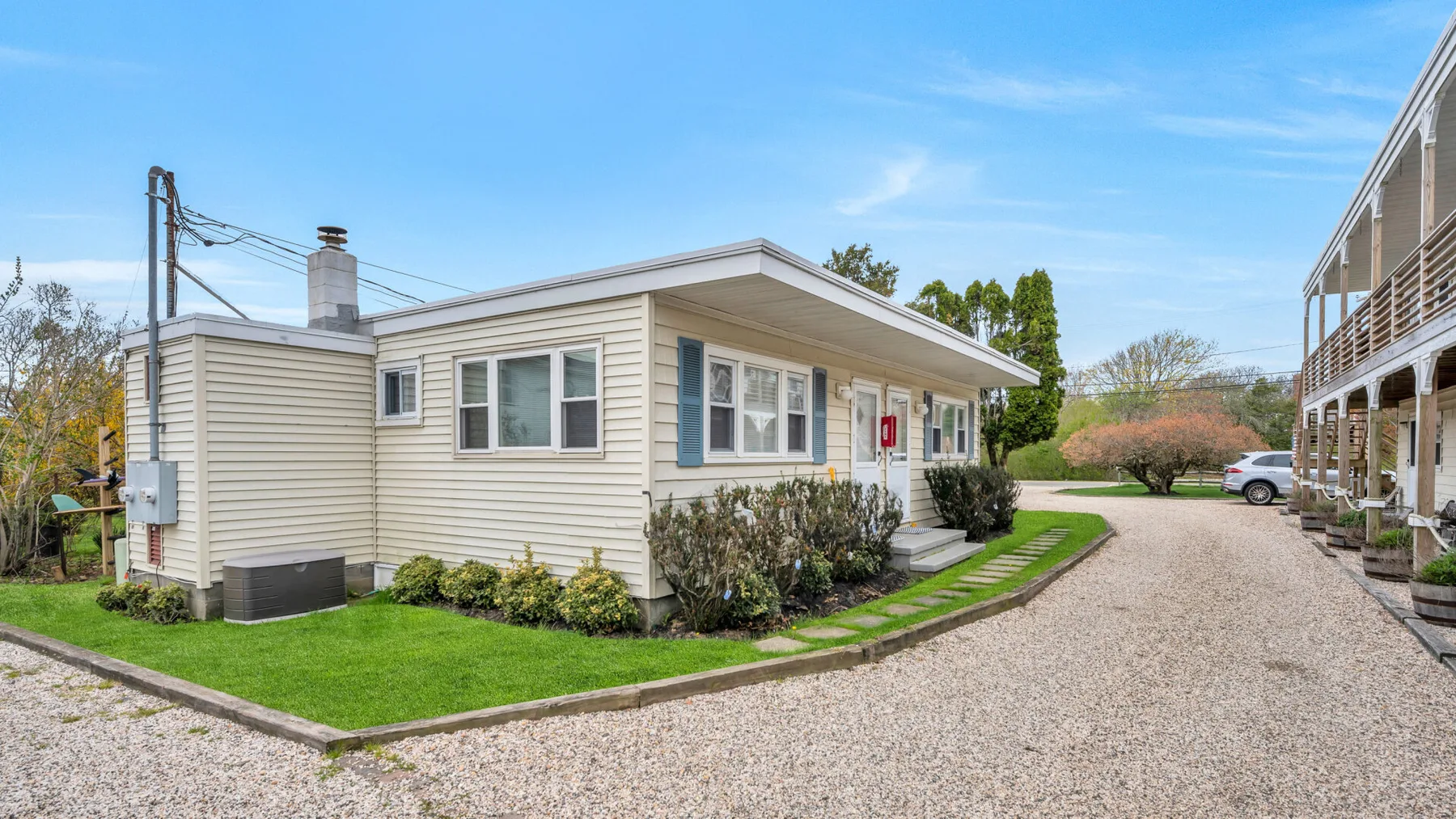 A single-story building beside a gravel driveway and landscaped lawn.