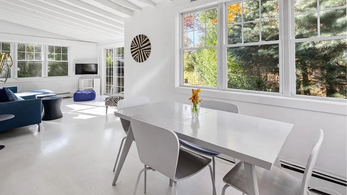 A bright dining area with a white table beside large windows.