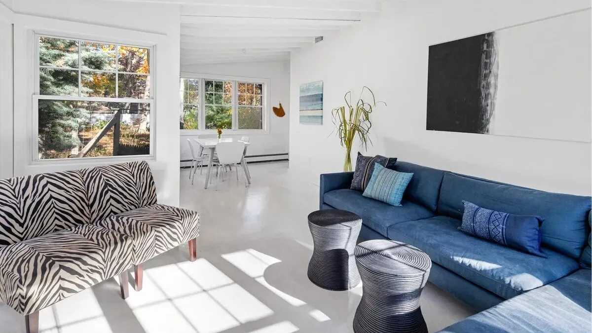 A bright living room with blue seating and large windows.