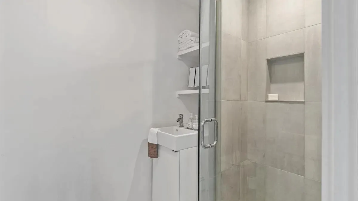 A bathroom with a wall-mounted sink beside a glass shower.