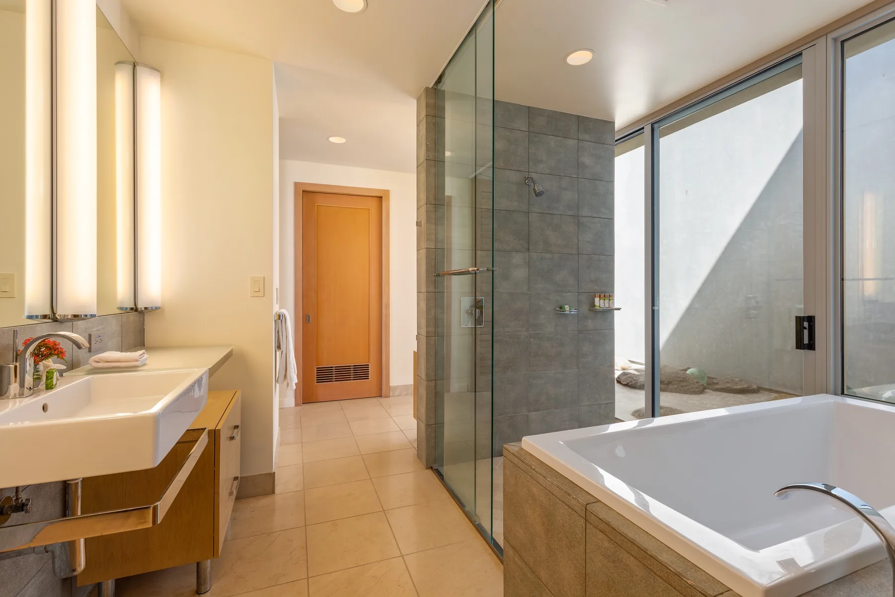 Un baño moderno con ducha de vidrio, bañera y amplias ventanas.