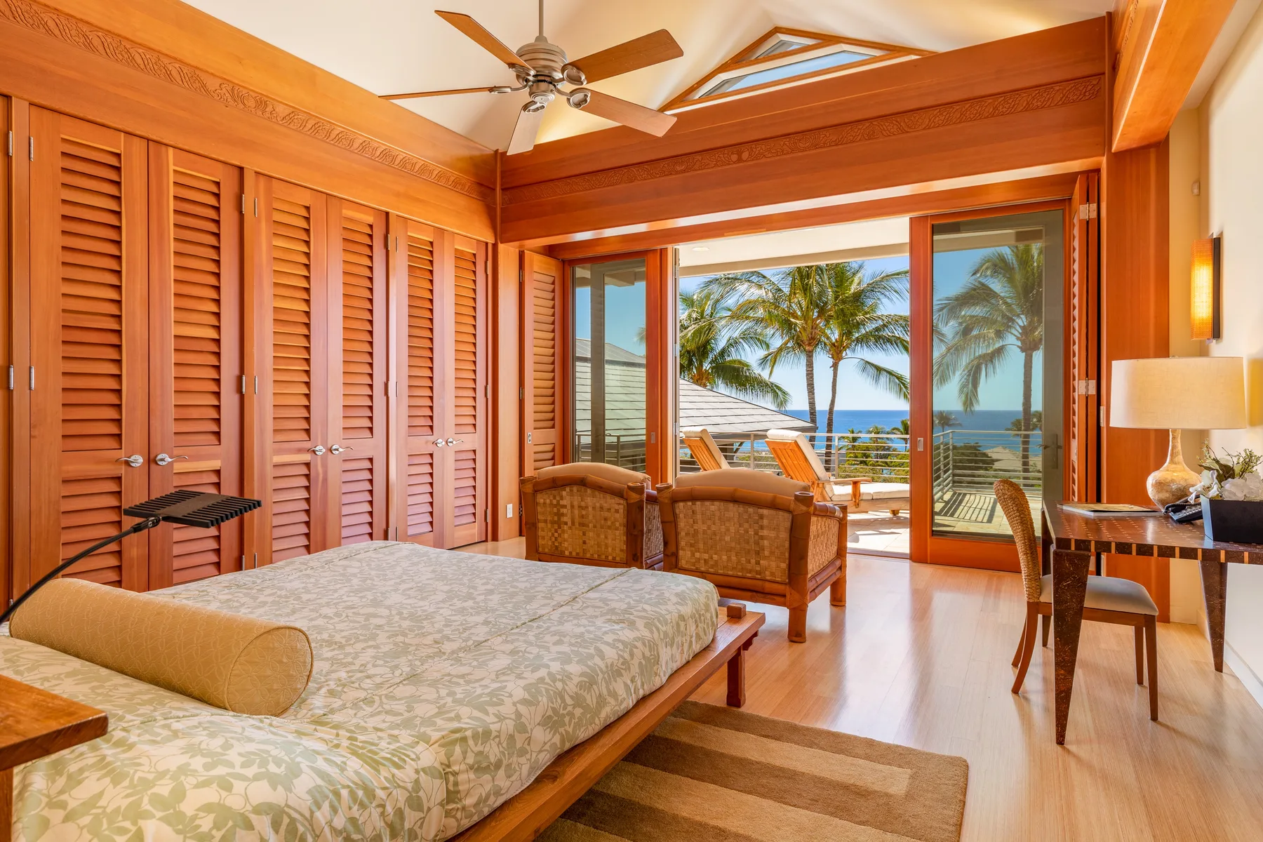 Un dormitorio se abre a un balcón con palmeras y vistas al mar.