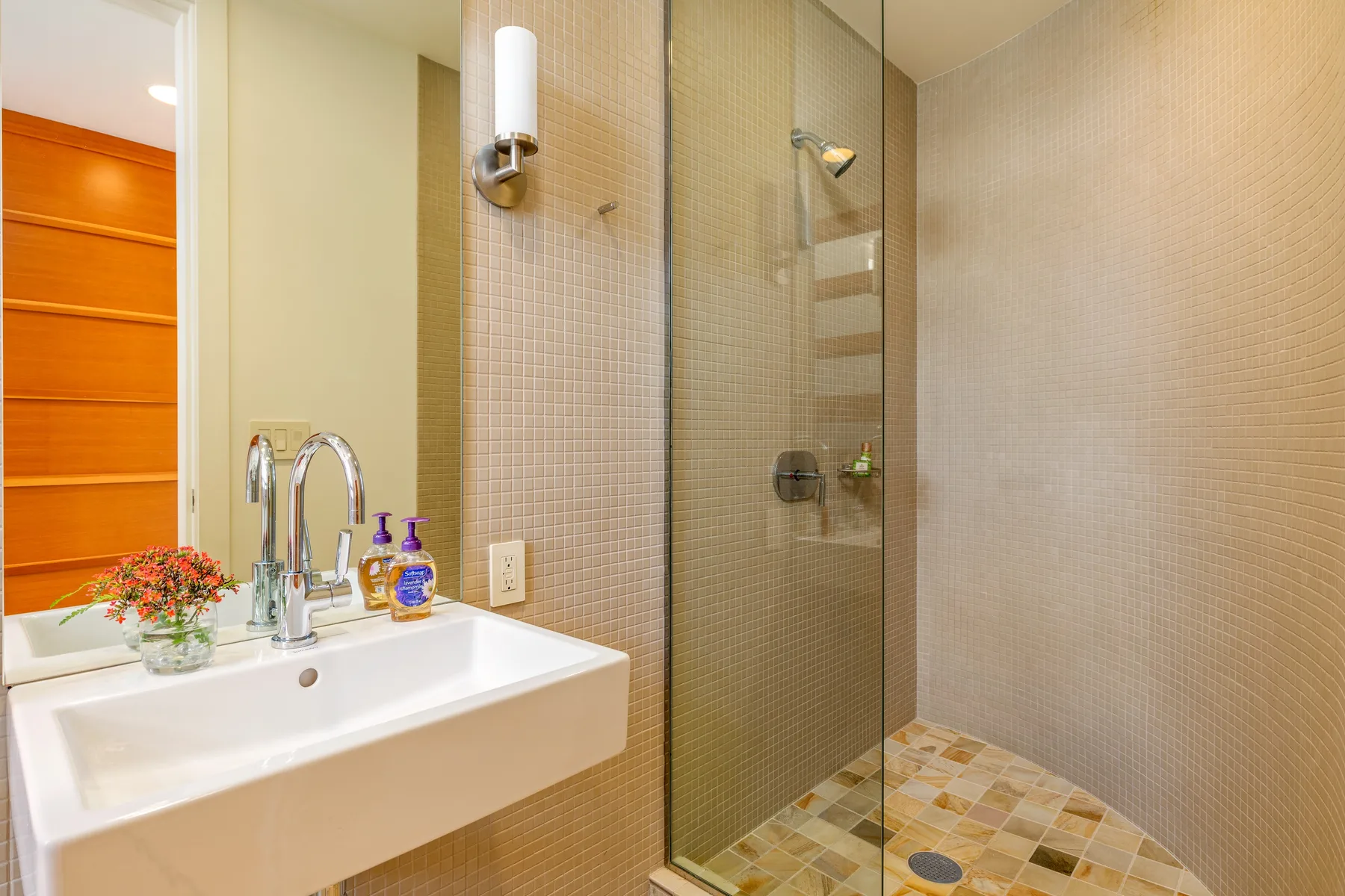Un baño con lavabo junto a una ducha de vidrio.