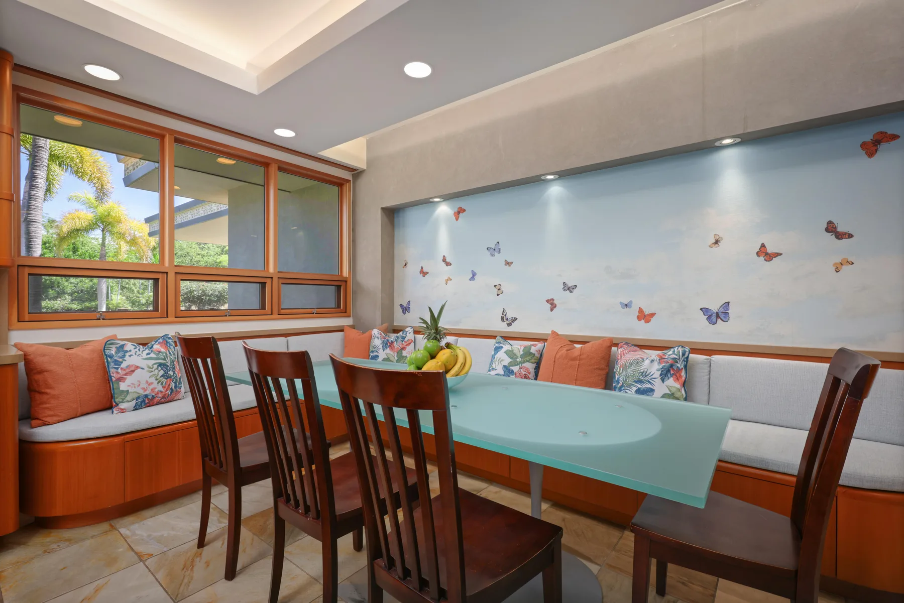 Un comedor tiene una mesa turquesa, asientos de madera y mariposas decorativas en la pared.