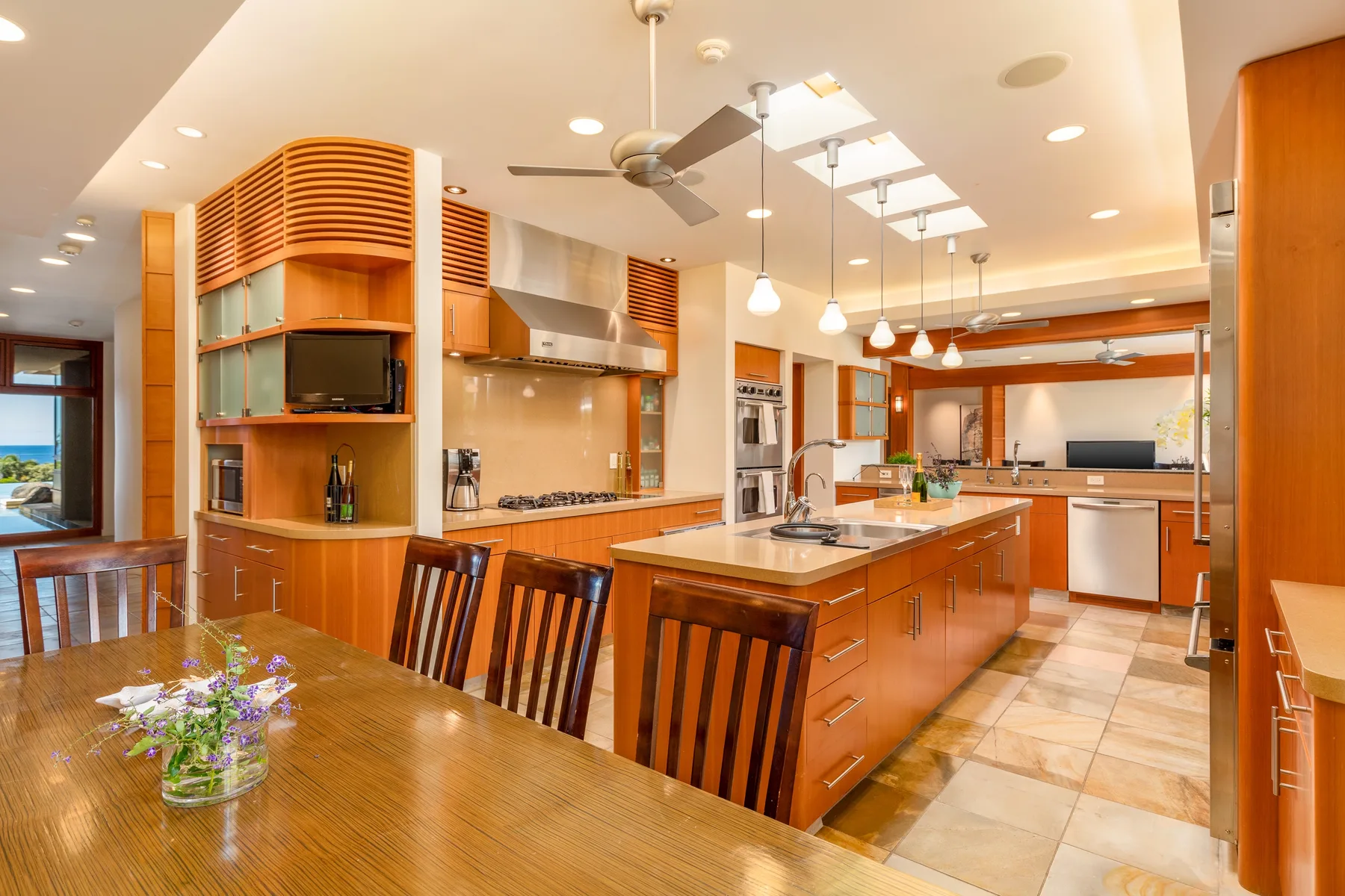 Una cocina y comedor abiertos y luminosos, con gabinetes de madera y una isla larga.