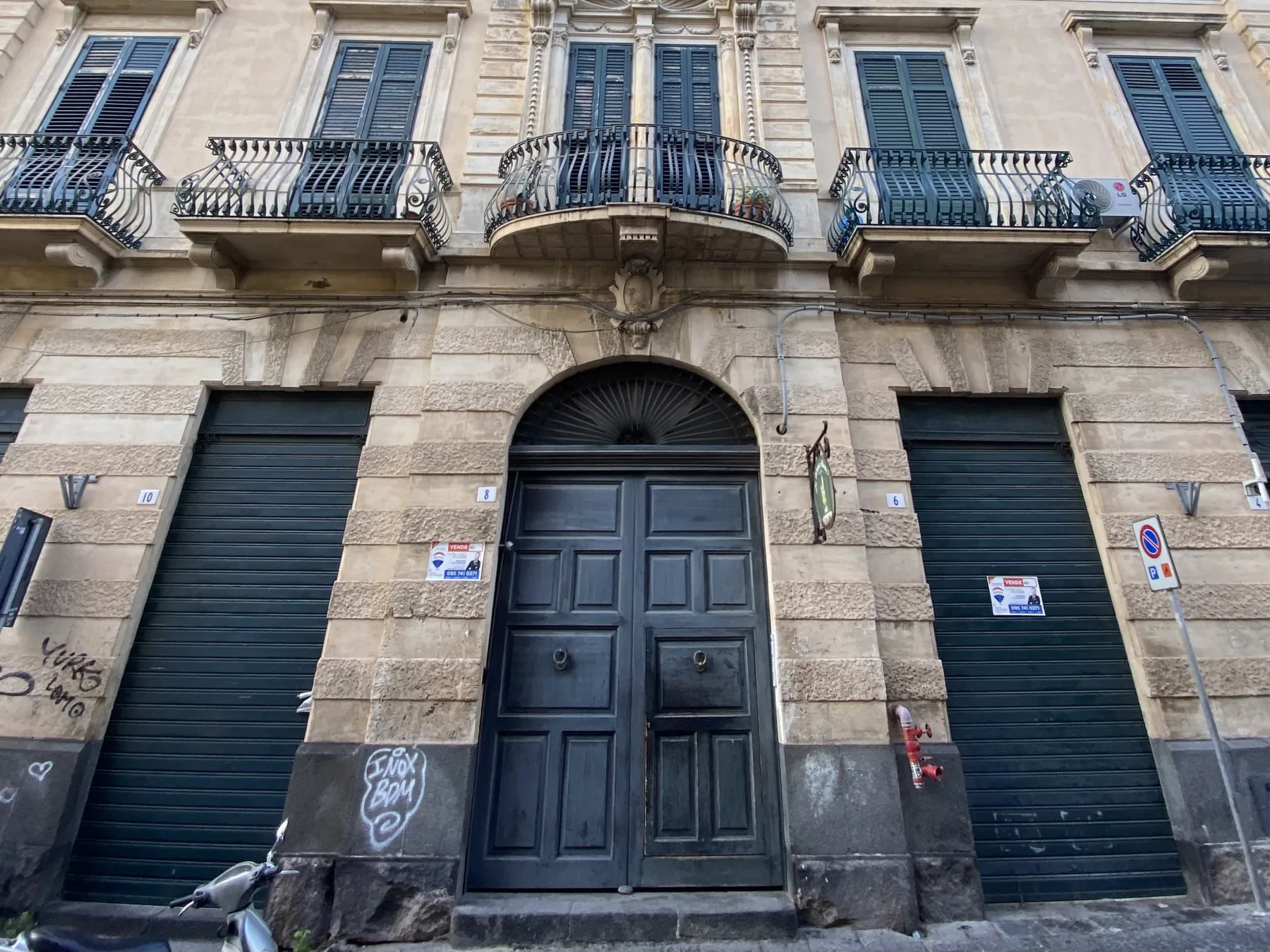 A stone building facade with a central dark doorway and balconies above.