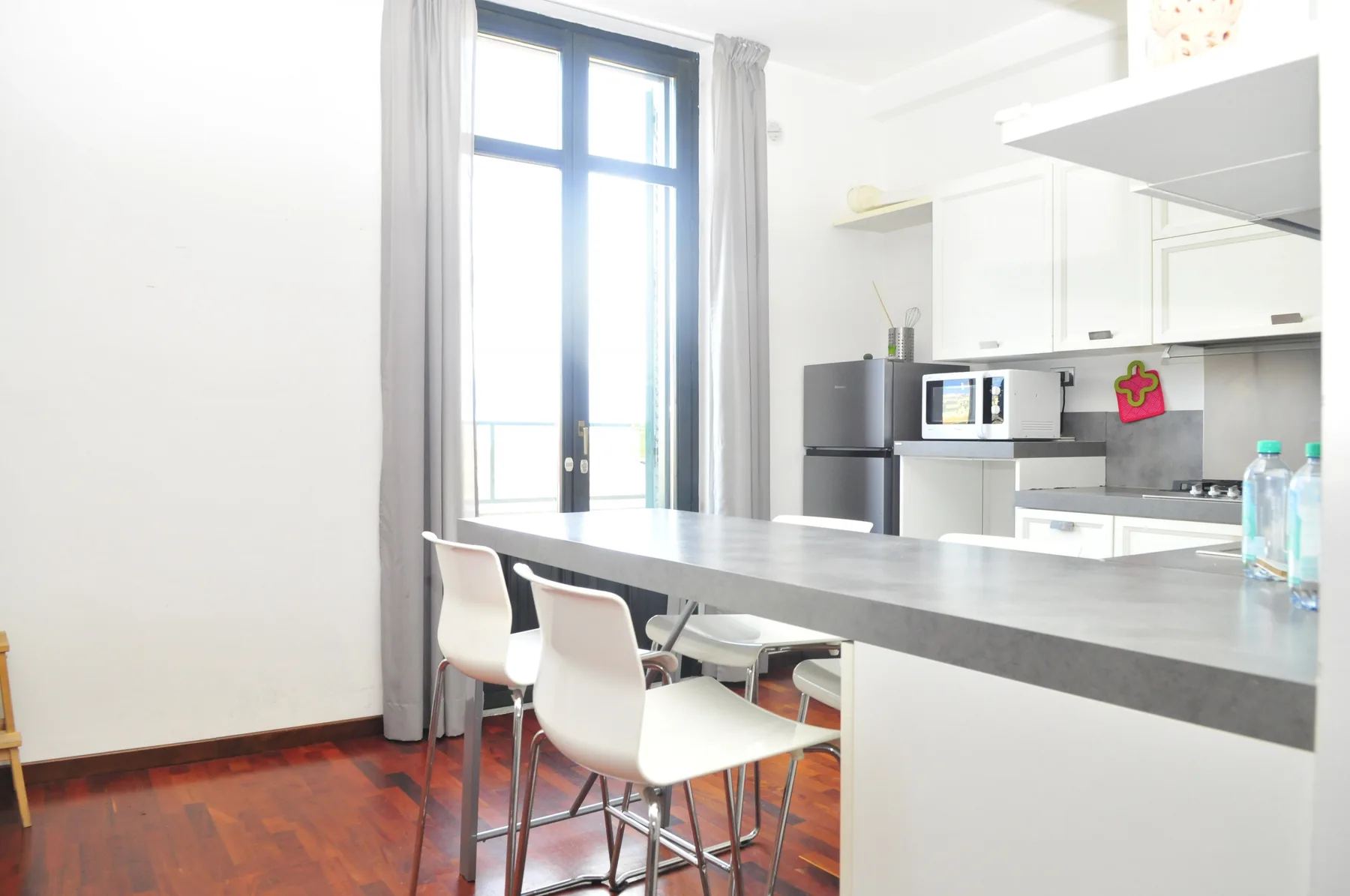 A bright kitchen and dining area with a long counter and white seating.