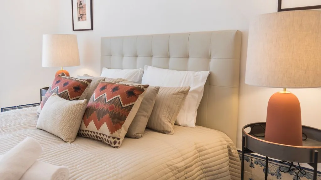 Un dormitorio con una cama bien hecha y lámparas a ambos lados.