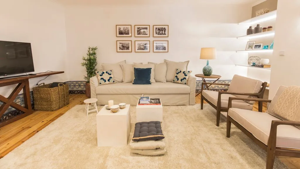 Una sala de estar luminosa con un sofá beige y una mesa de centro baja.