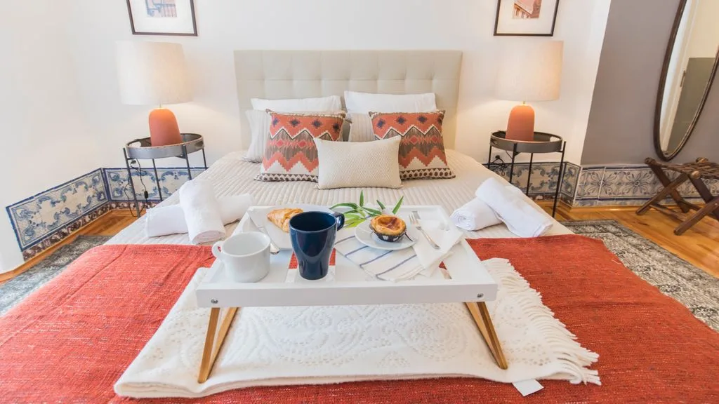 Un dormitorio con una cama y una mesa baja con vajilla.