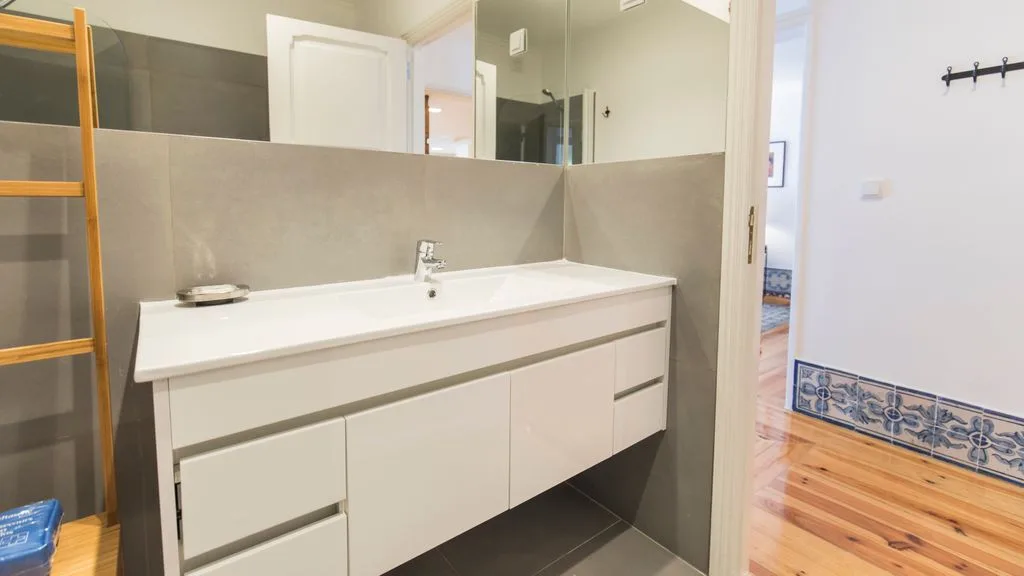 Un lavabo de baño con un espejo amplio y una estantería de madera.