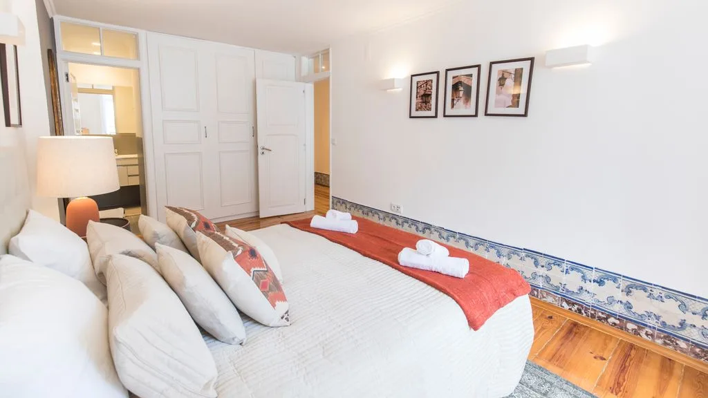Un dormitorio con una cama, toallas dobladas y cuadros en la pared.