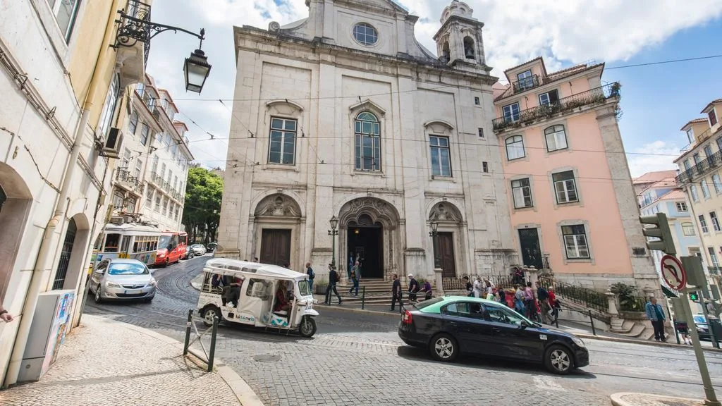 Una calle empedrada pasa junto a una iglesia de piedra y edificios de colores.