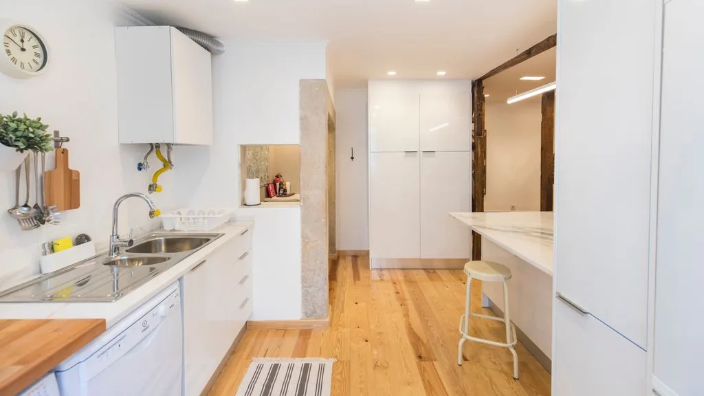 Una cocina luminosa con armarios blancos y una encimera larga.
