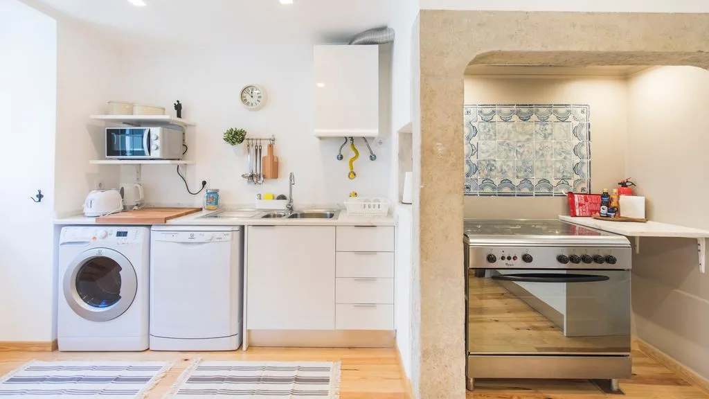 Una cocina luminosa con una lavadora junto a la encimera y la estufa.