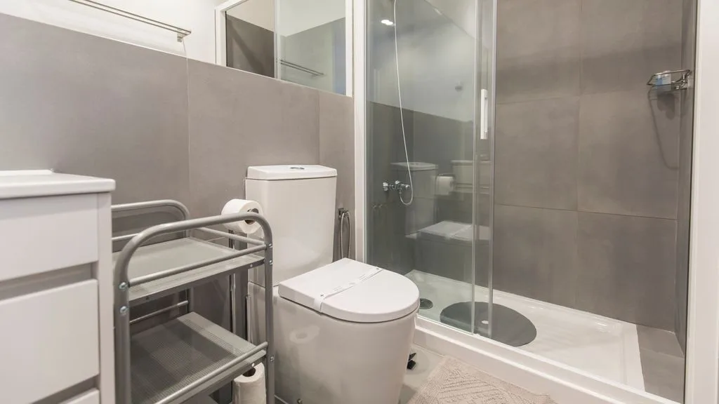 Un baño alicatado con inodoro, lavabo y bañera con ducha.