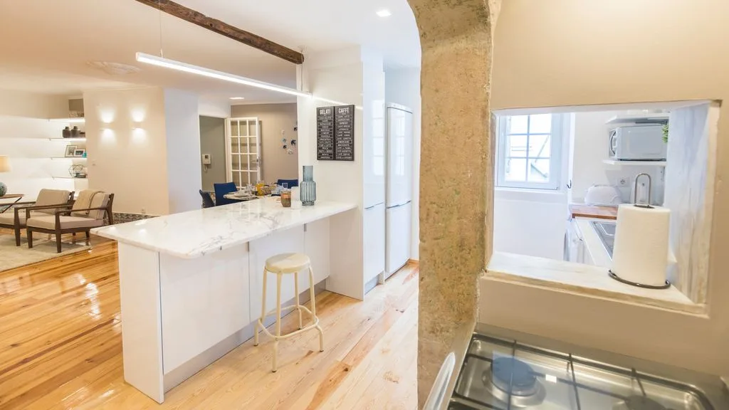 Una cocina y comedor luminosos con una isla blanca y suelo de madera.