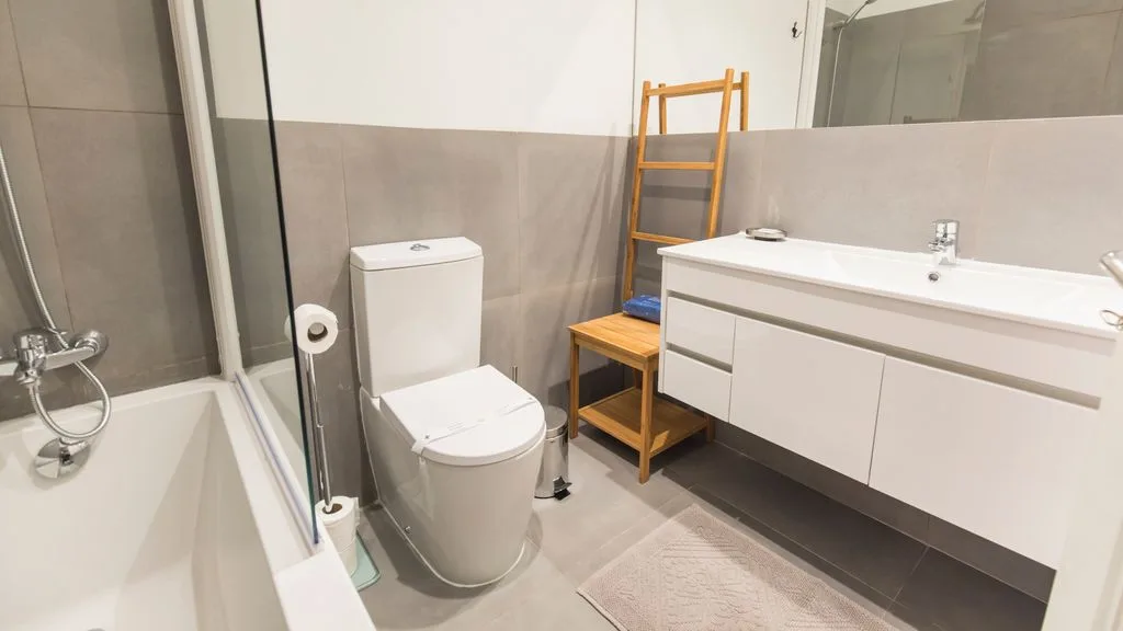 Un baño con bañera, inodoro y mueble de lavabo blanco.