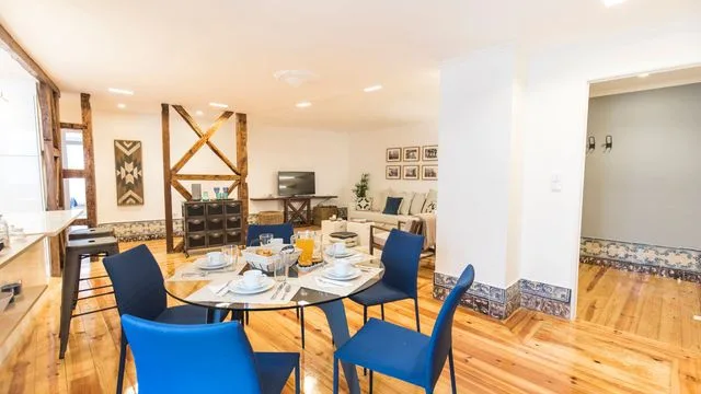 A bright dining area has a set table with blue seating and wooden floors.