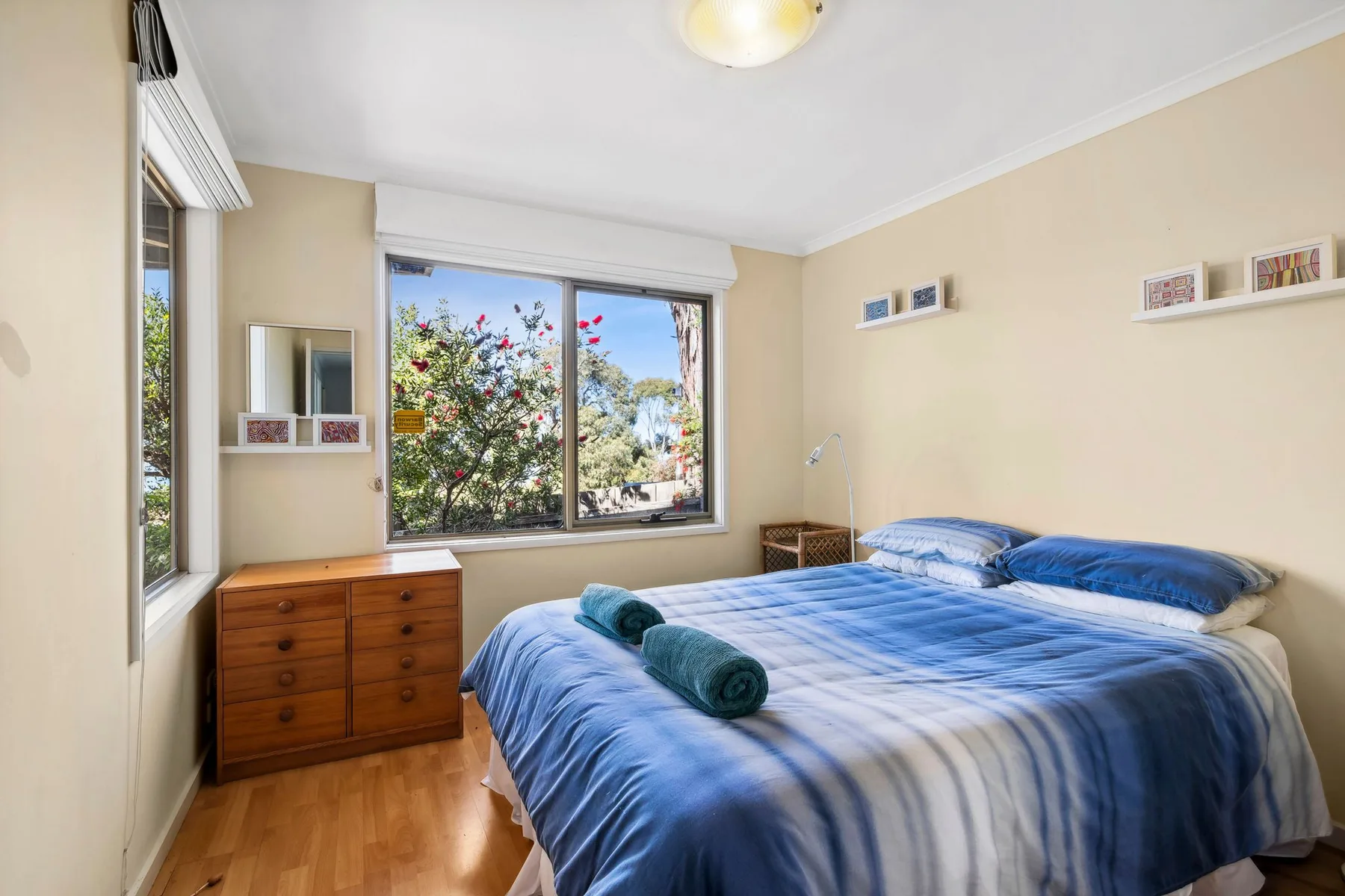 Un dormitorio con una cama azul junto a una ventana grande.