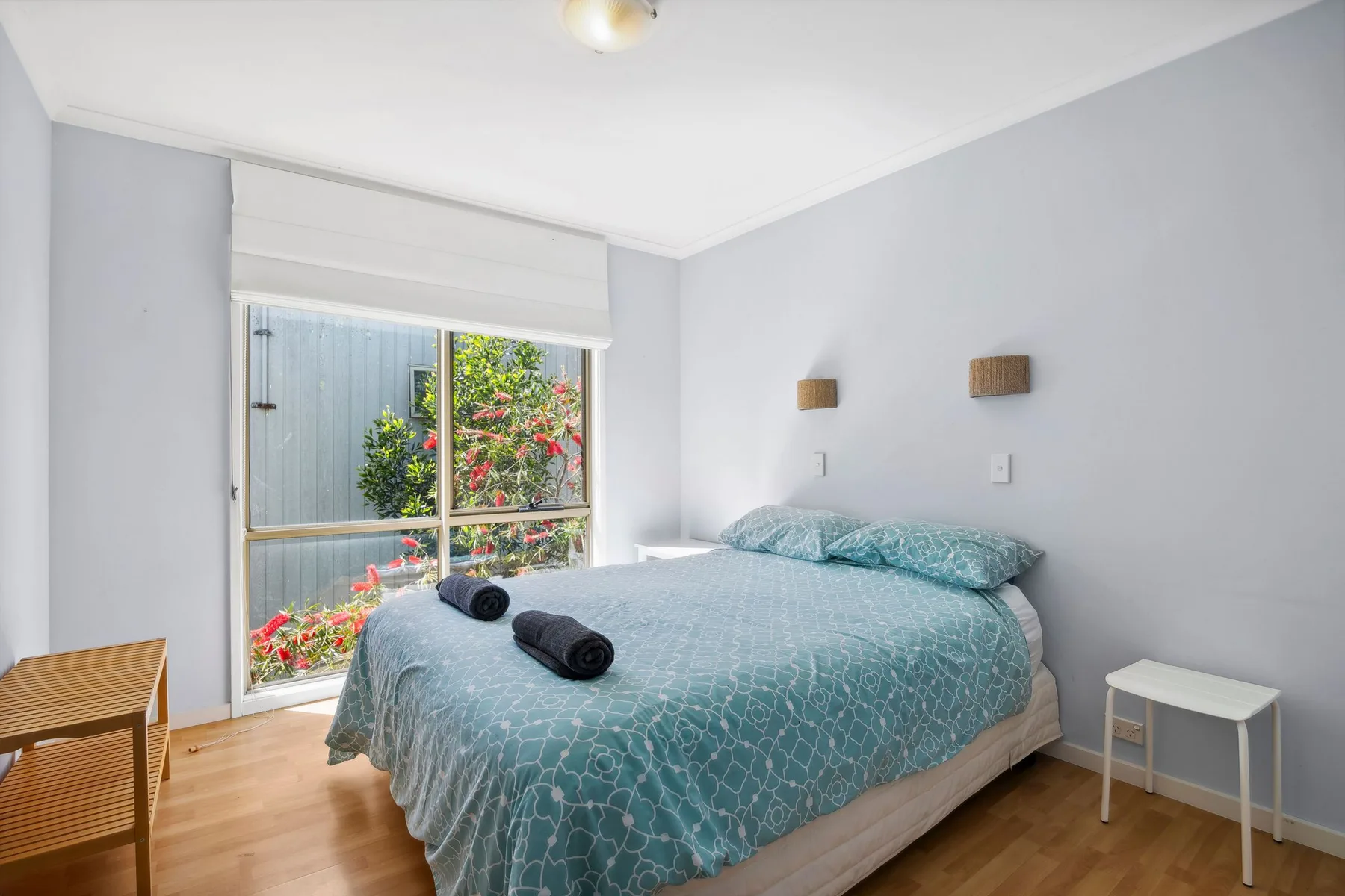 Un dormitorio con una cama junto a una ventana grande con vistas a la vegetación.