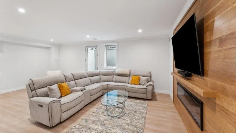 A bright living room with sectional seating and a wall-mounted television.