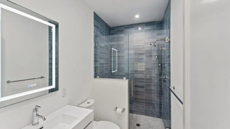 A bathroom with a sink, mirror, and tiled shower.